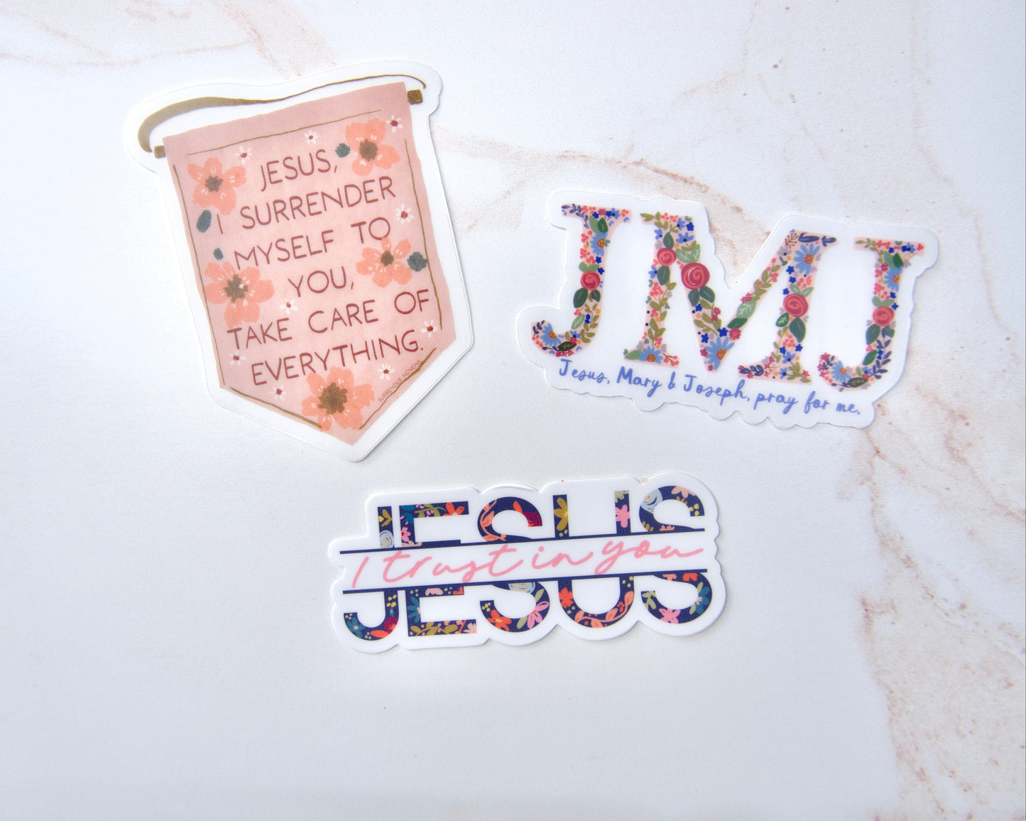 Three Catholic faith stickers featuring Jesus, Mary & Joseph, Jesus I Trust In You, and Surrender Novena designs for water bottles and school supplies.