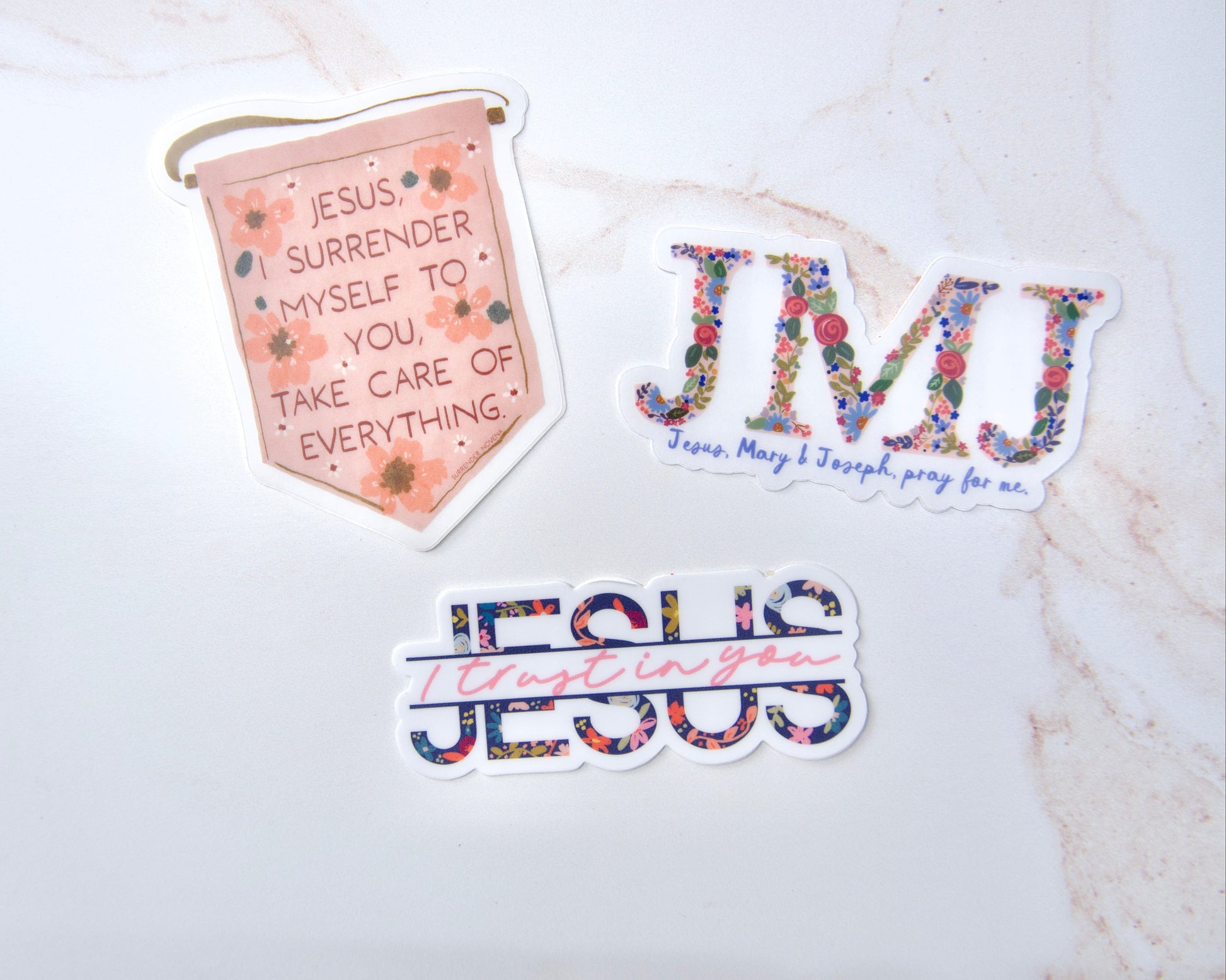 Three Catholic faith stickers featuring Jesus, Mary & Joseph, Jesus I Trust In You, and Surrender Novena designs for water bottles and school supplies.